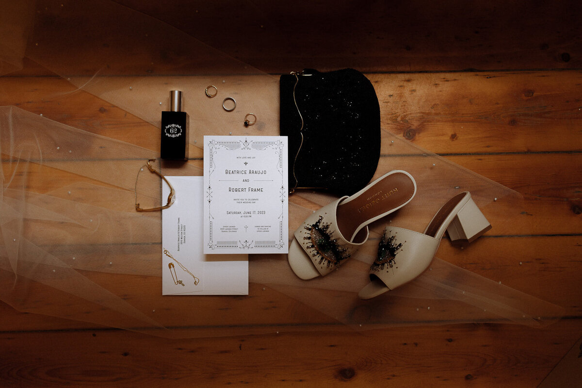 Wedding day details with hints of black including shoes, perfume, jewelry, and the invitation.