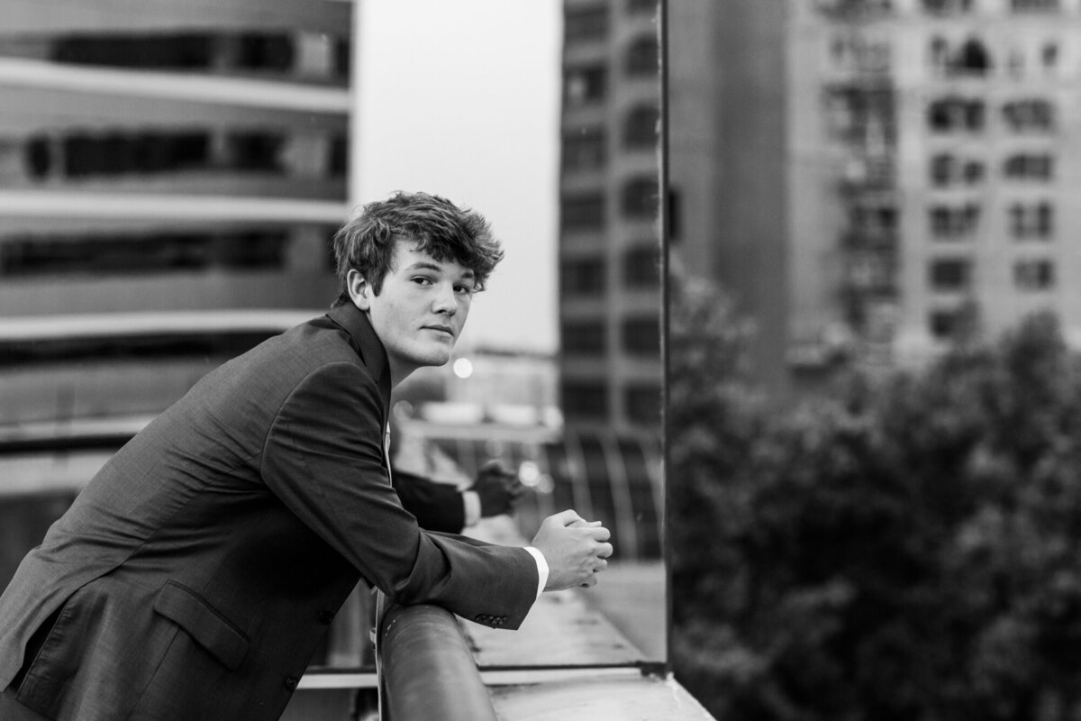 Black and white urban portrait of a high school senior guy on a rooftop