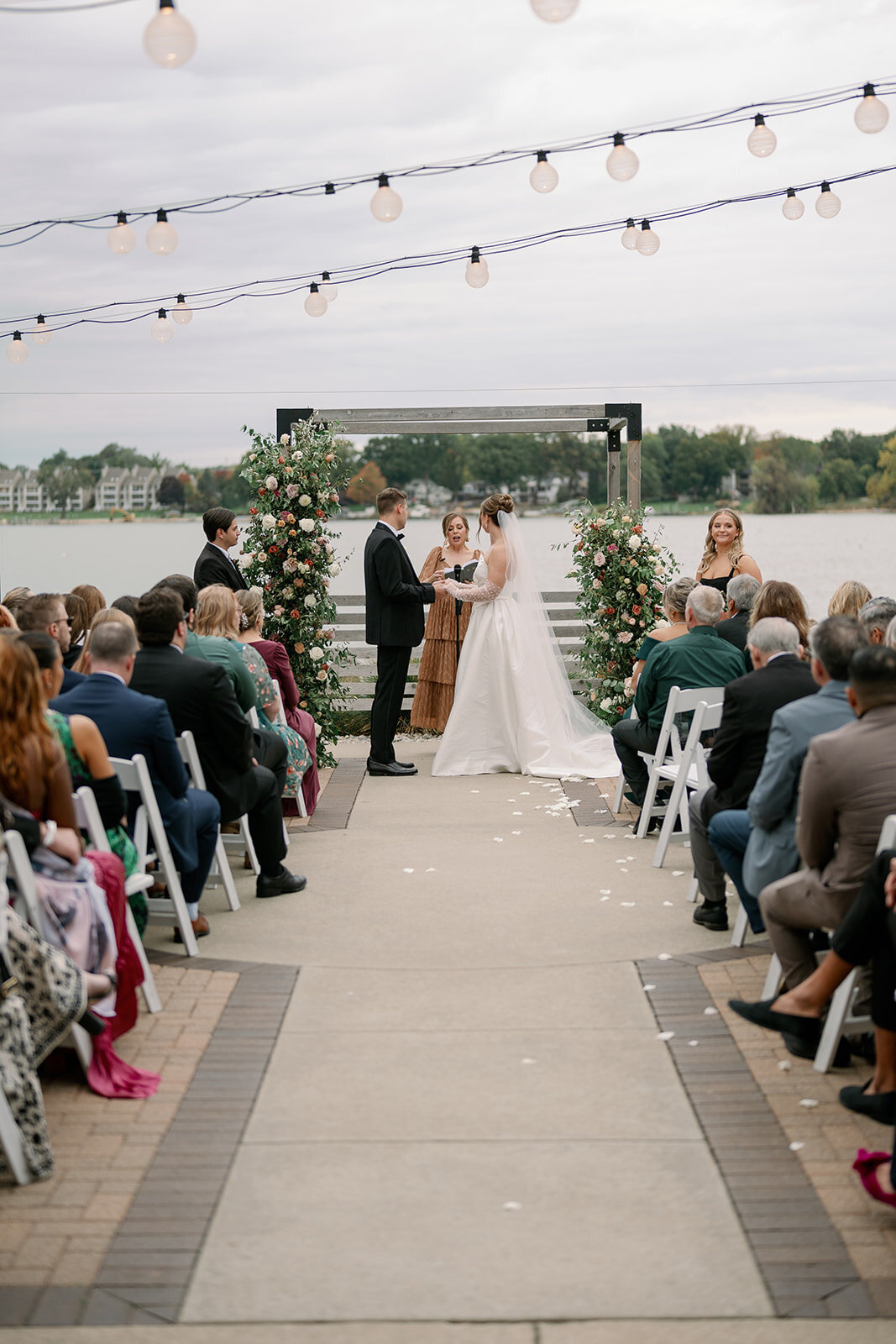 A bride and groom share their vows during their outdoor ceremony at Boatwerks Wedding Venue in Holland, MI