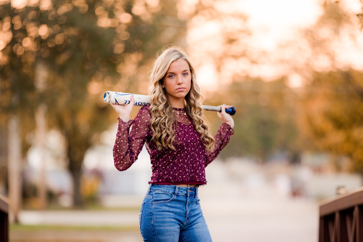 High schooler poses with her baseball bat.