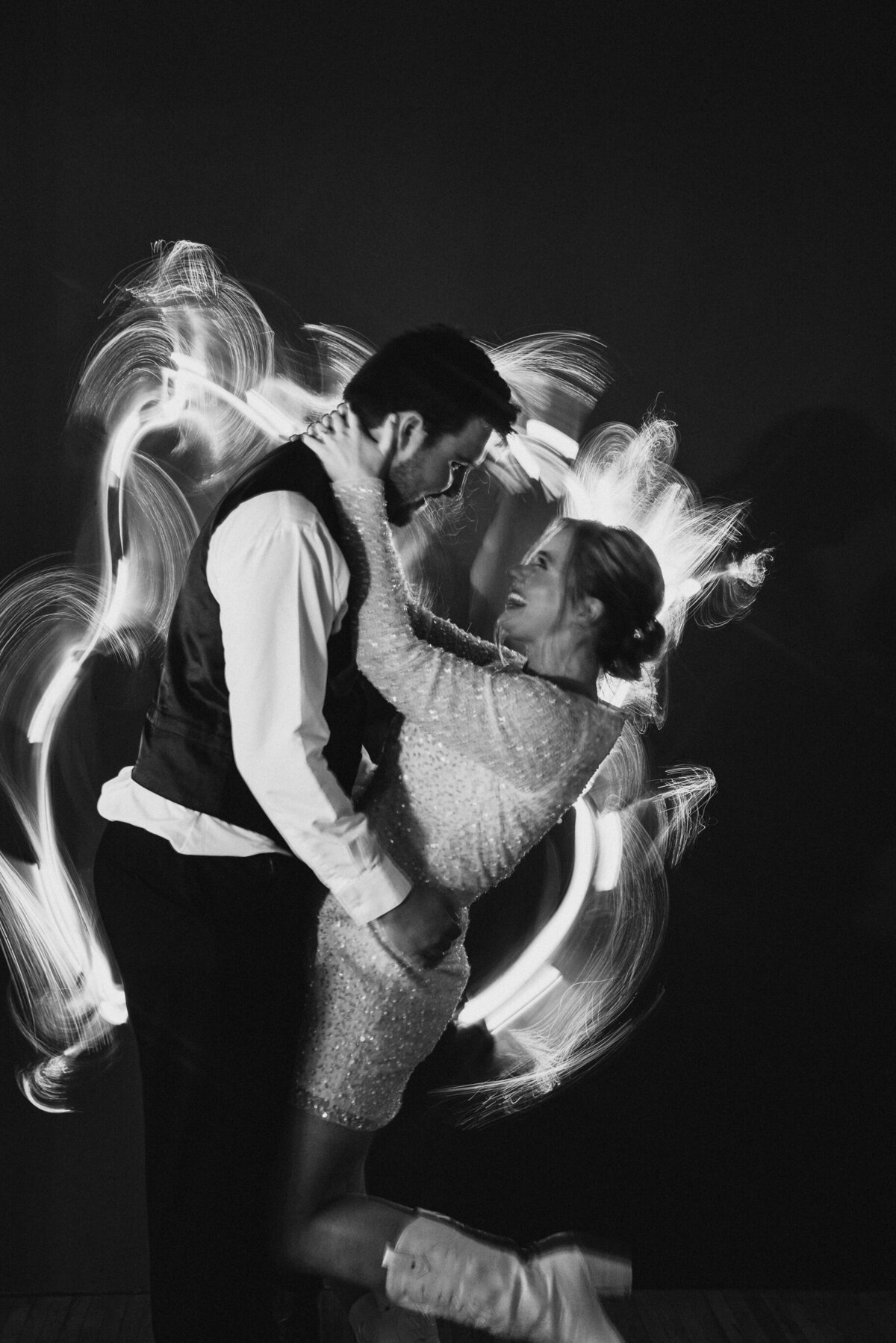 bride and groom in their after party outfits with light painting behind them for a creative long exposure portrait