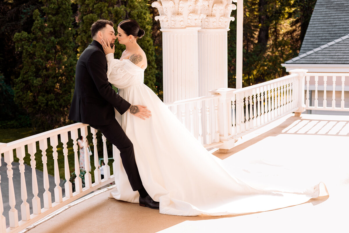 bride and groom start to lean in for a kiss on a balcony at the norland estate in lethbridge