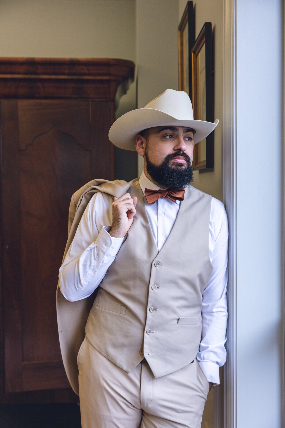 Groom in cowboy hat adjusting jacket before wedding ceremony