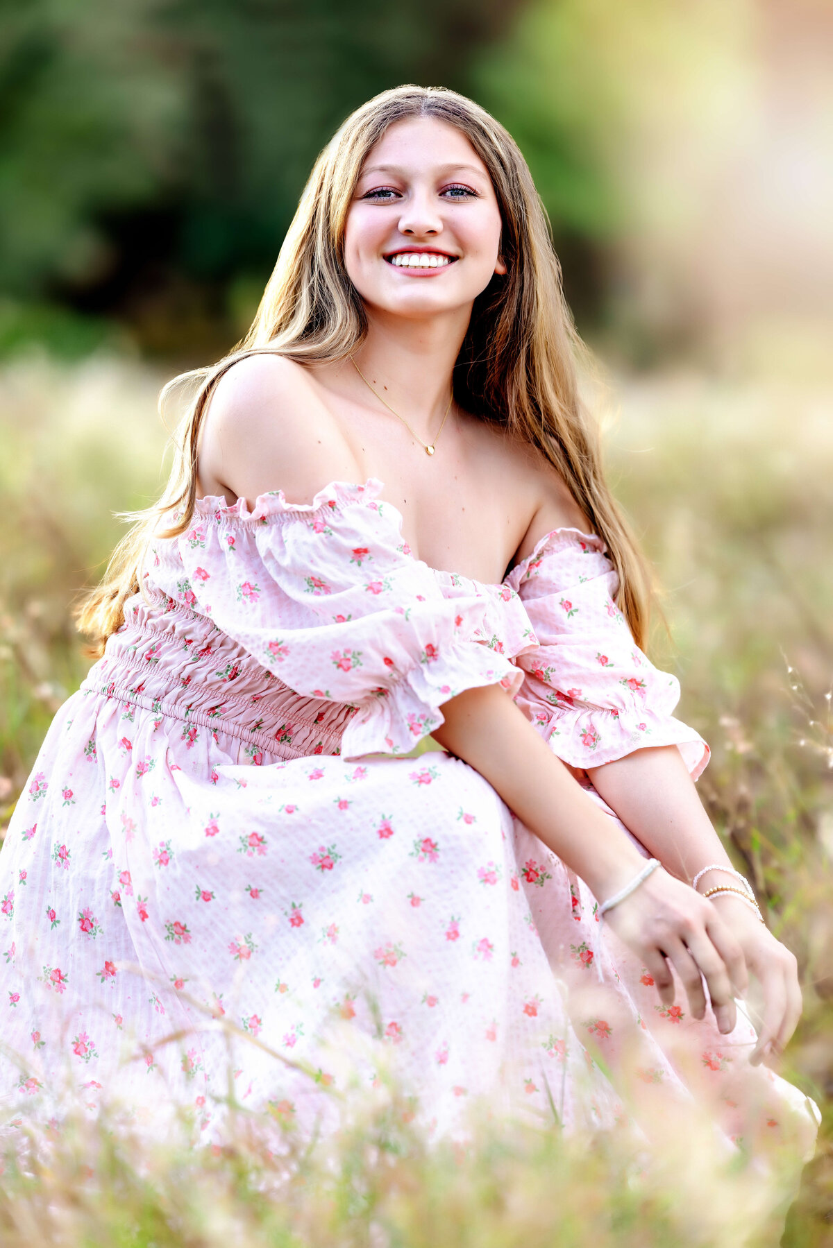 Natural light senior portrait of girl in floral dress sitting in tall grass in Winter Garden, Florida