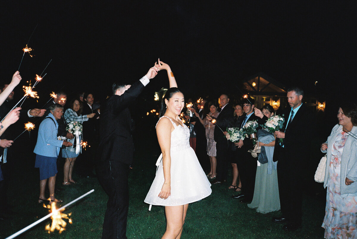 Bride twirling short reception dress during nighttime sparkler send-off at Springfield Manor in Maryland.