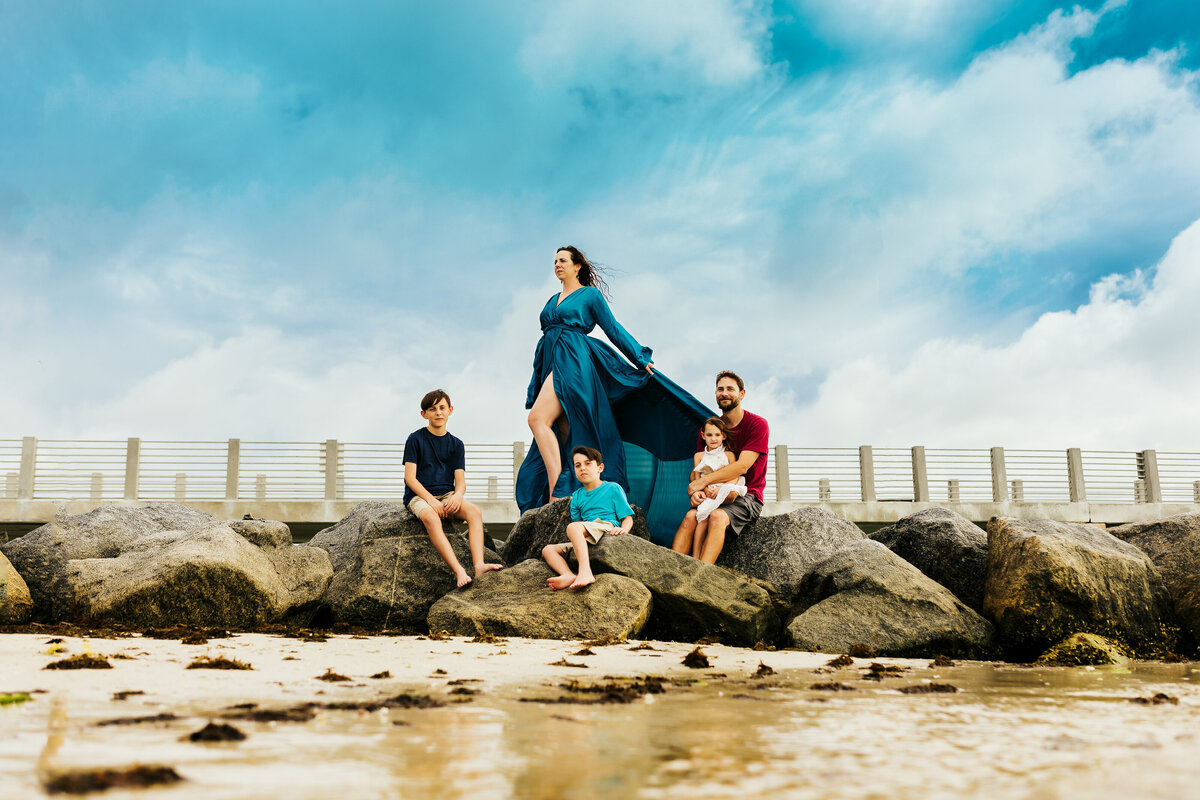 a artistic family portrait at the beach with a large family standing on rocks  at fort desoto beach