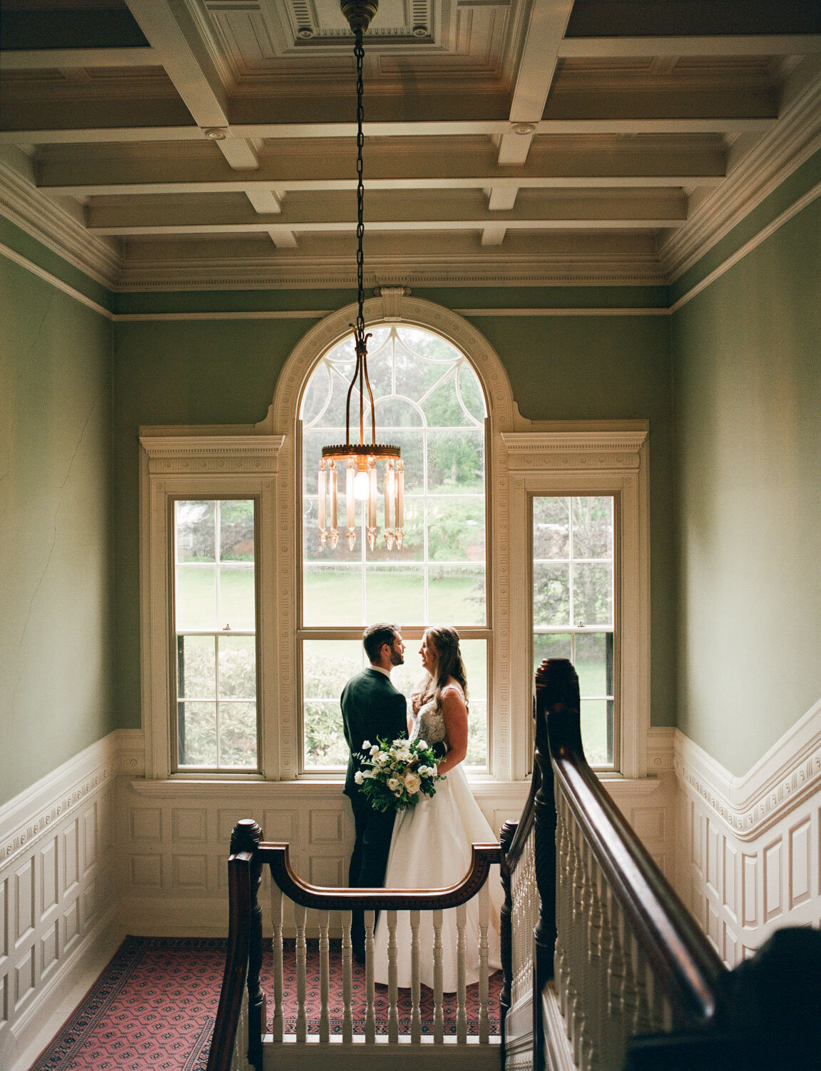 Bride and groom facing each other on the staircase