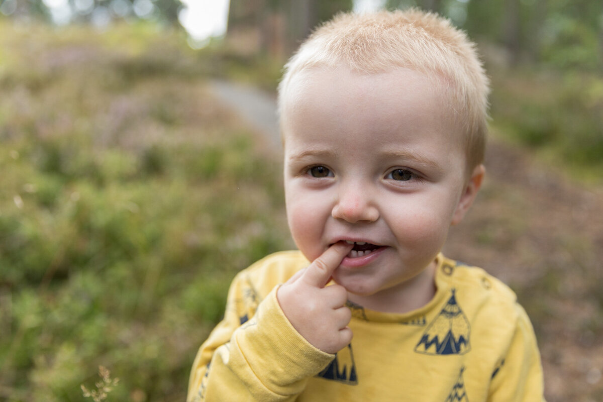 Livsstilsfoto nærbilde av en liten gutt som har fingeren i munnen etter å ha spist blåbær.