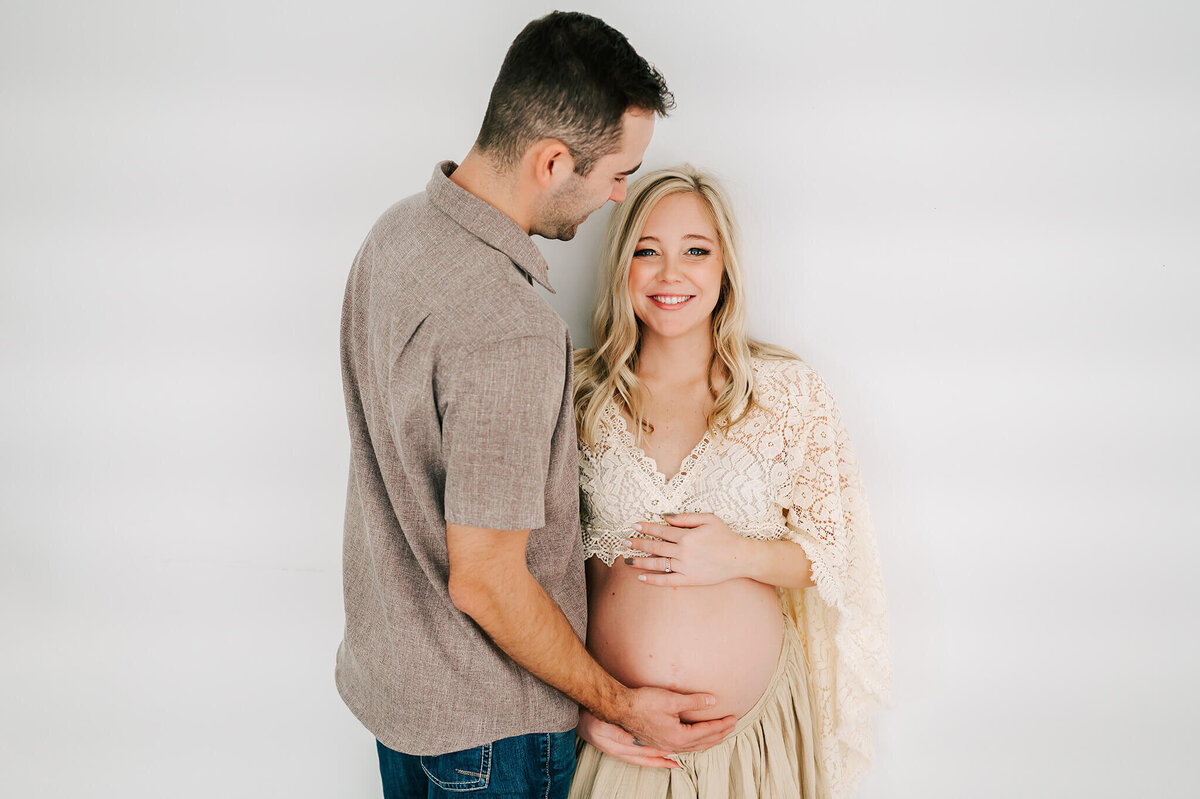pregnant mom leaning on wall with husband smiling at her captured by Jessica Kennedy of The XO Photography