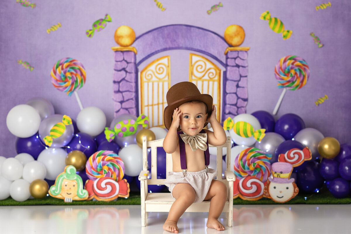 One year old Tampa baby enjoying a personalized luxury cake smash session with playful wonka themed decorations