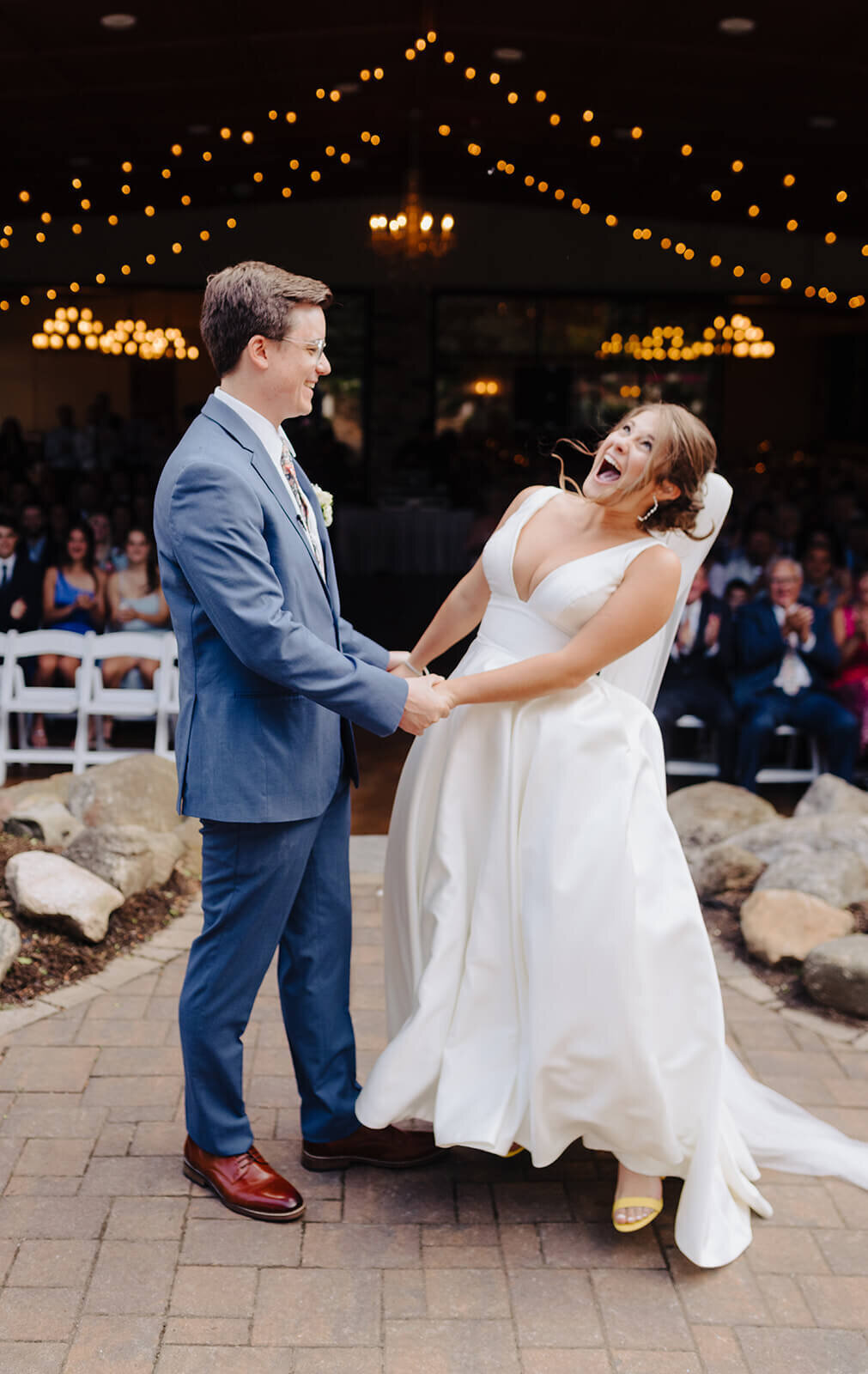 Bride and groom standing together laughing in front of wedding guests at Oswego wedding, NY