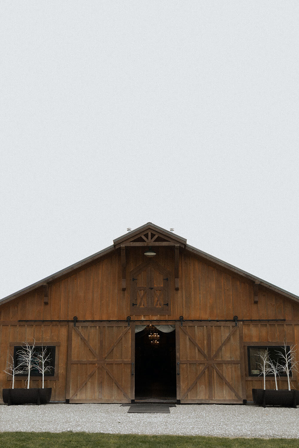 Front view of a barn venue with decorative trees placed outside
