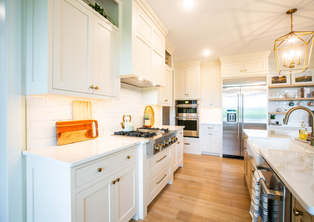 Open kitchen with white cabinets, large island, and quartz countertops in an Otsego custom home
