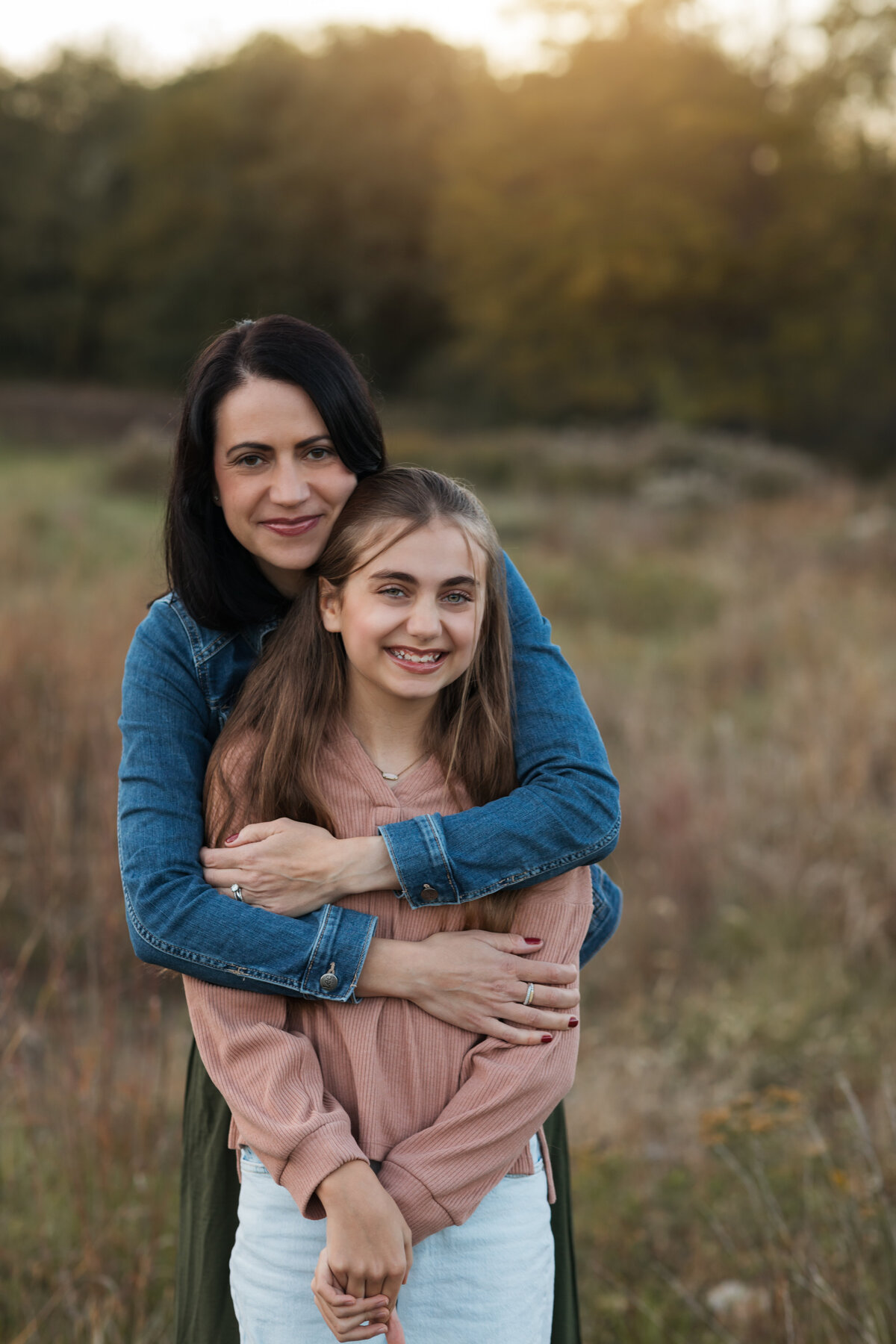mom hugging daughter for family photos in field