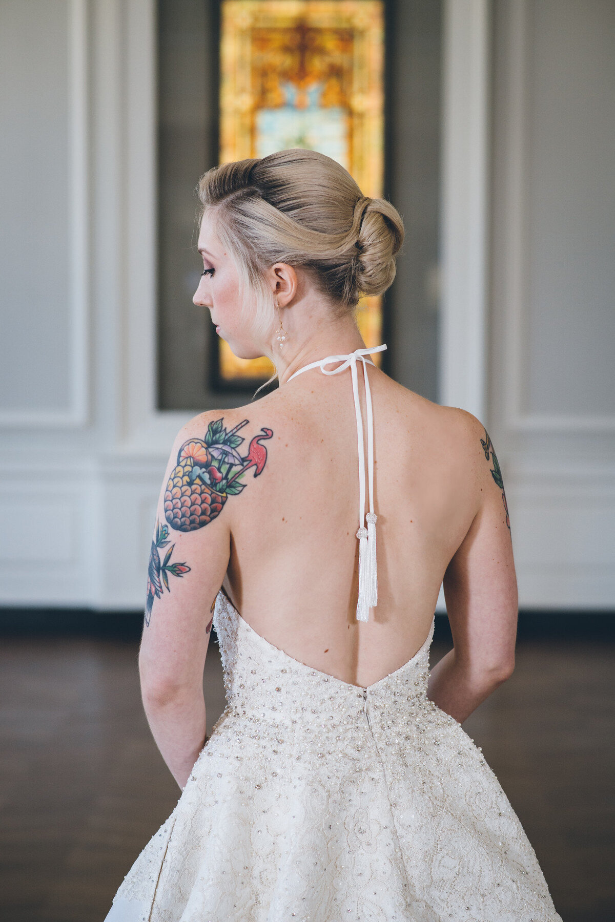 The halter top of the Karli wedding dress style creates an open back. The hand-beaded tassels on the ends of the halter ties hang down the middle of the back.