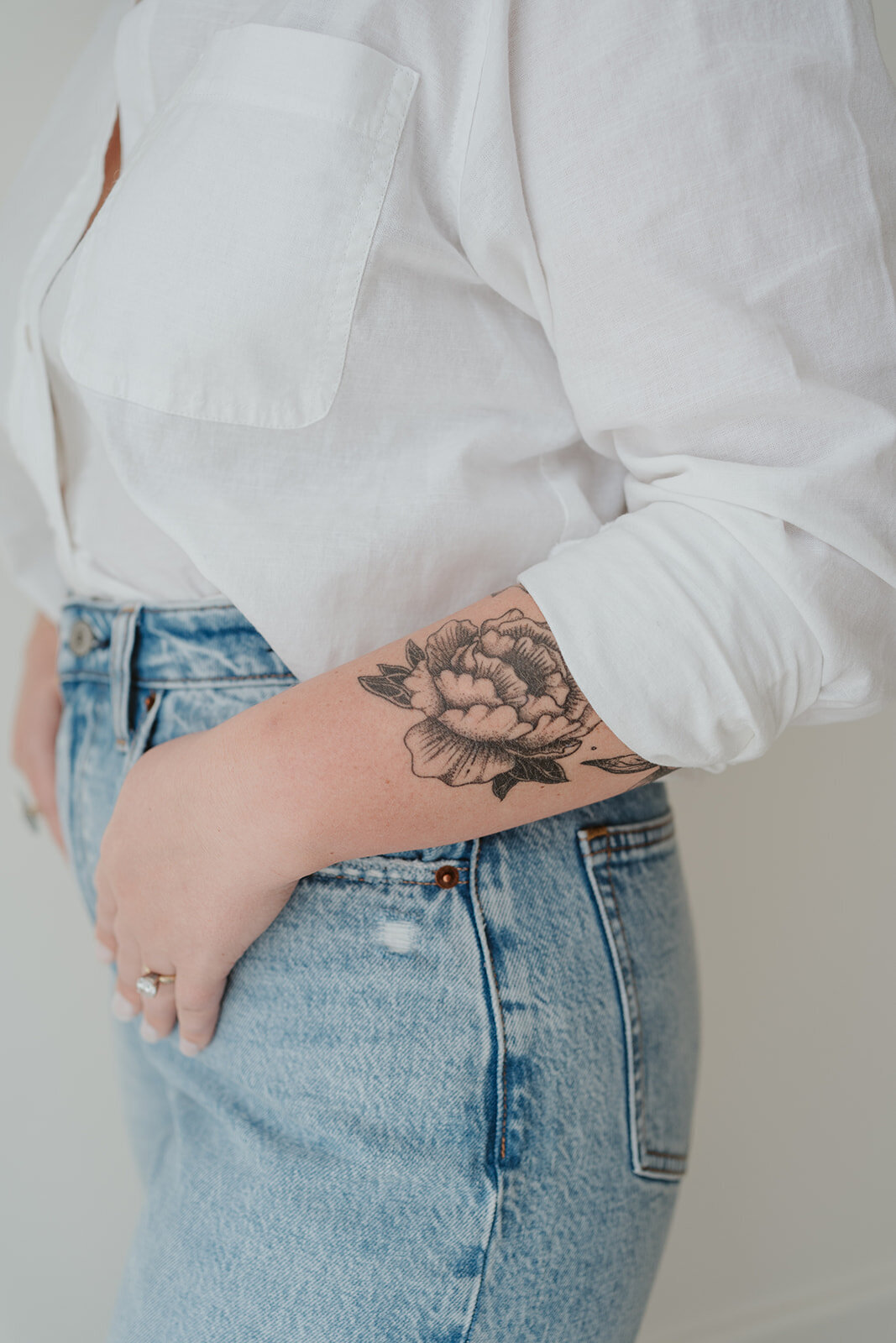 Close-up photo highlighting a floral arm tattoo and denim jeans during a Wildher and Co studio branding session.