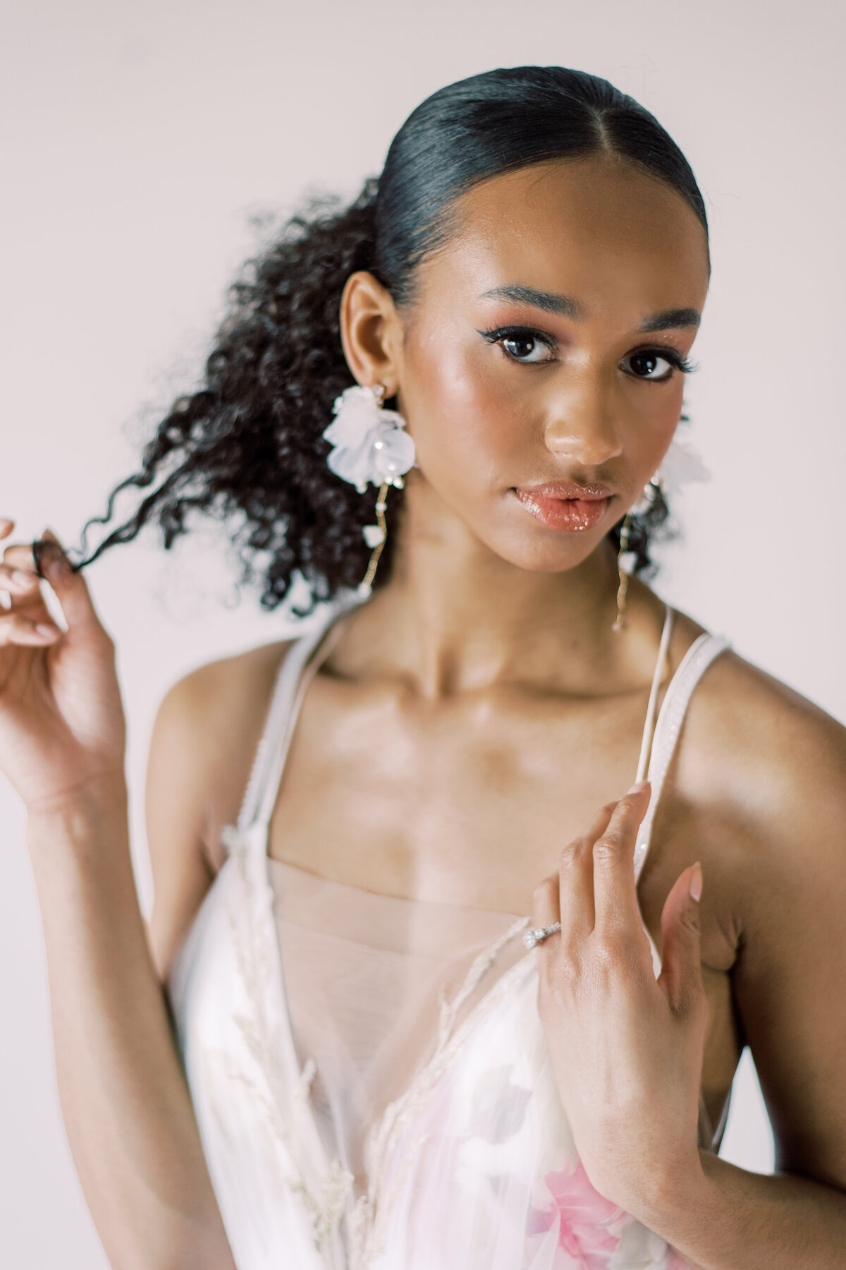 Bride holding curly hair , with her hand rested on her chest with her ring showing