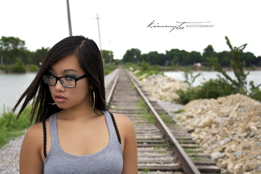 Girl deep in thought standing on railroad tracks