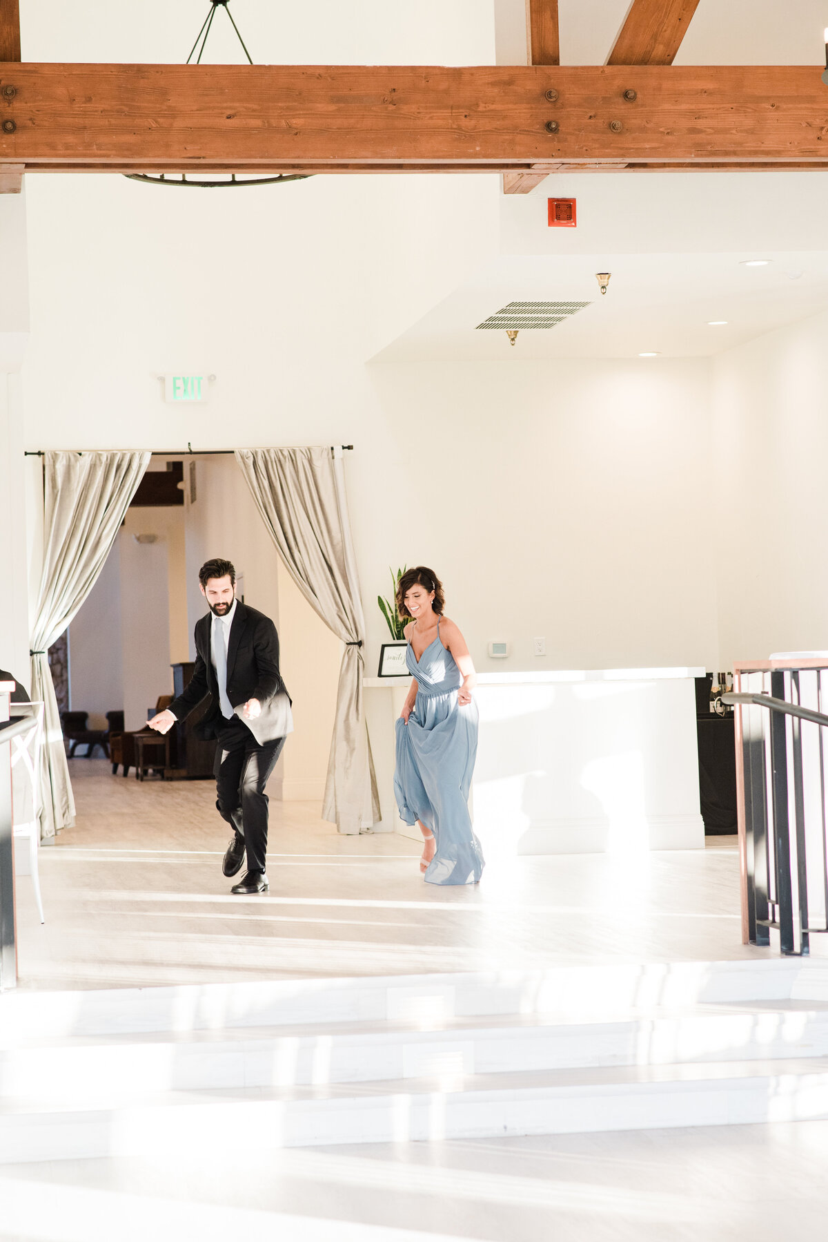 Denver wedding photographer captures the maid of honor and best man dancing into the reception space for the grand entrance at The Oaks