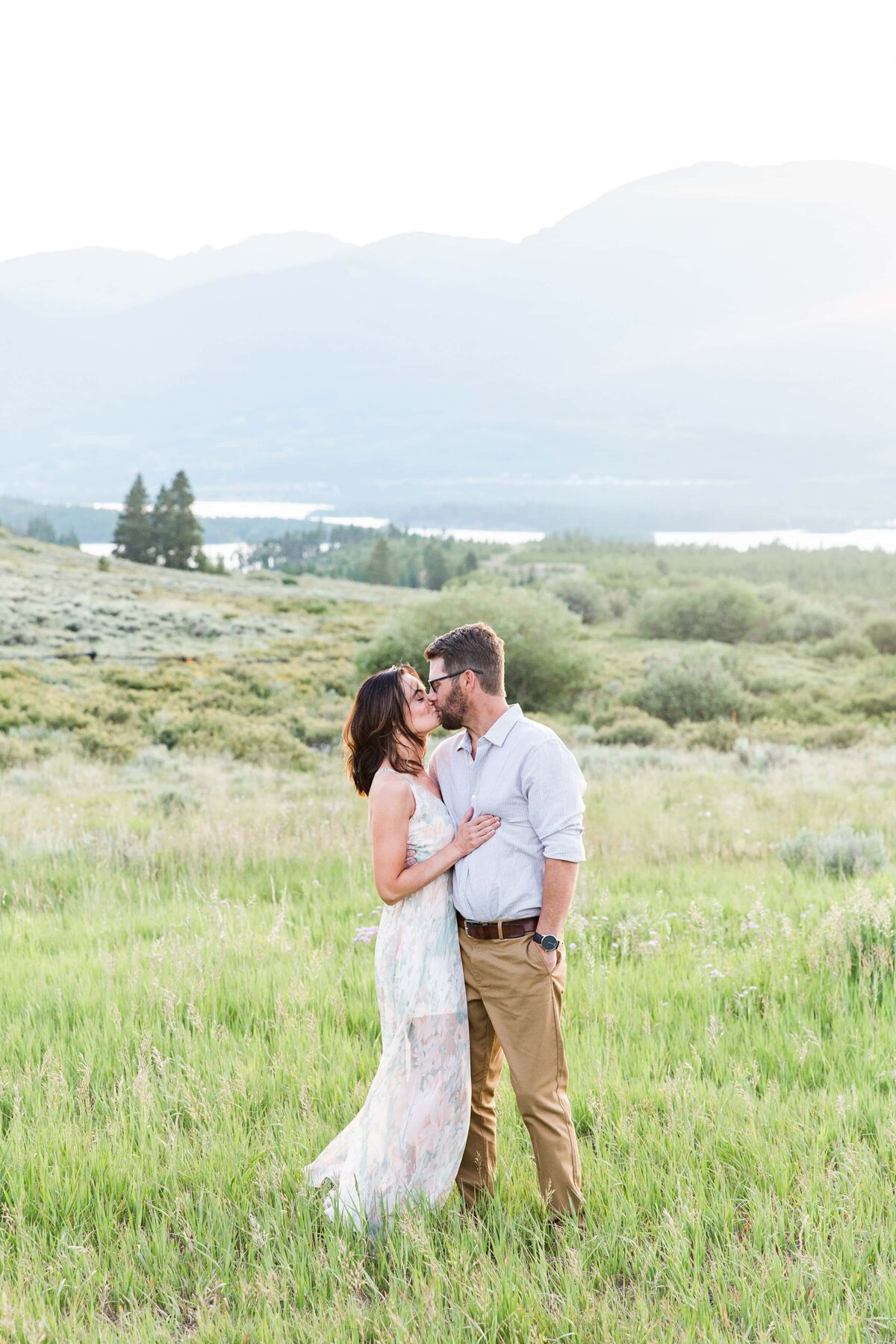 husband and wife kiss in front of Dillon Lake, CO