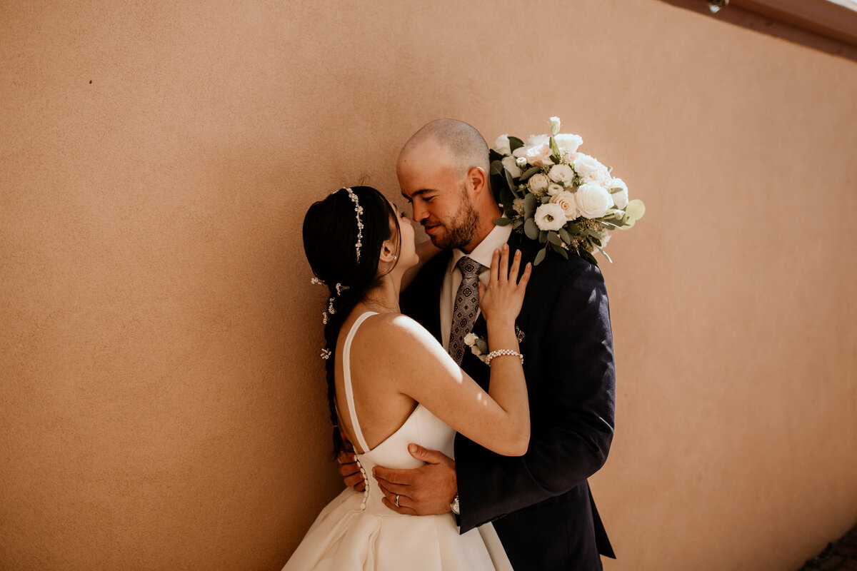 bride and groom holding each other in front of a southwest wall