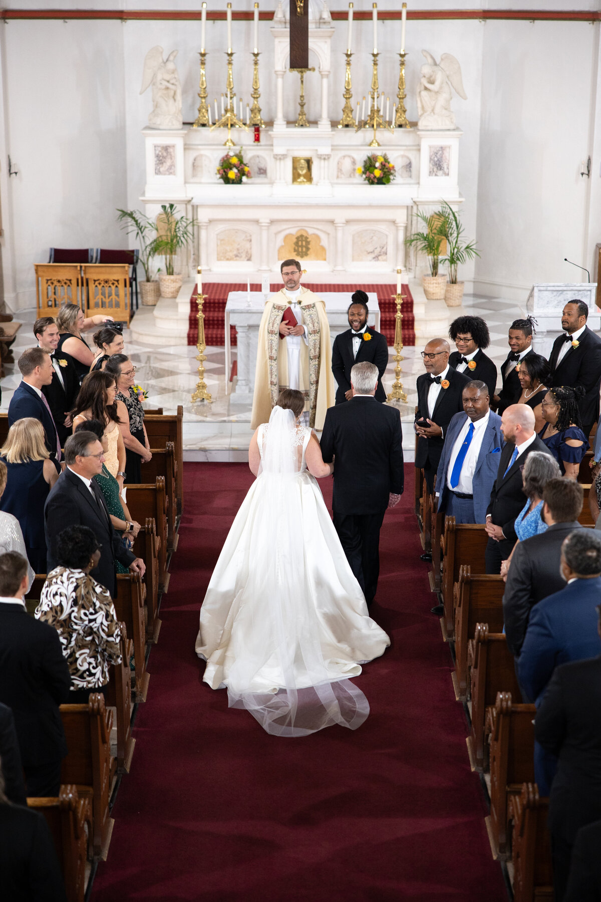 Bride adjusting cathedral-length veil before Catholic wedding ceremony in Washington DC church.
