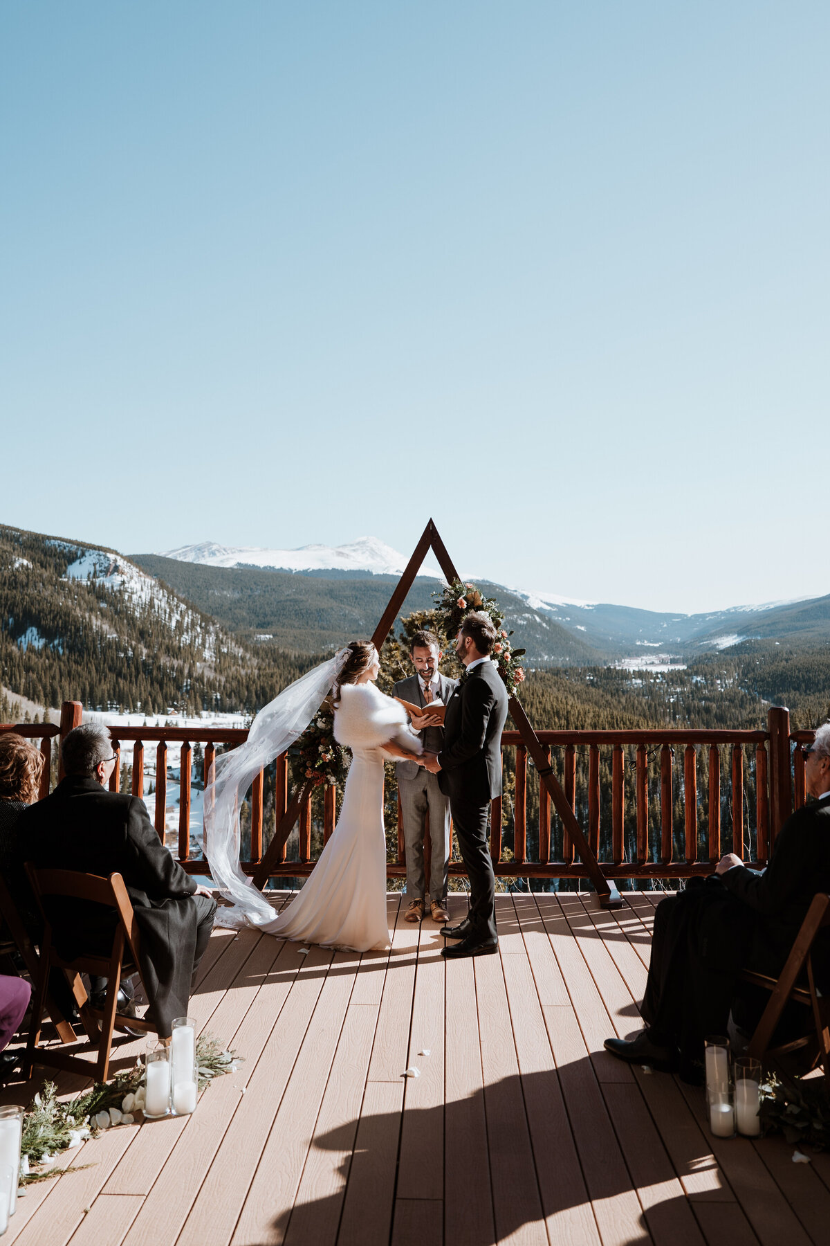 Deck ceremony at the Lodge at Breckenridge with triangle arch and sweeping mountain views under blue sky.