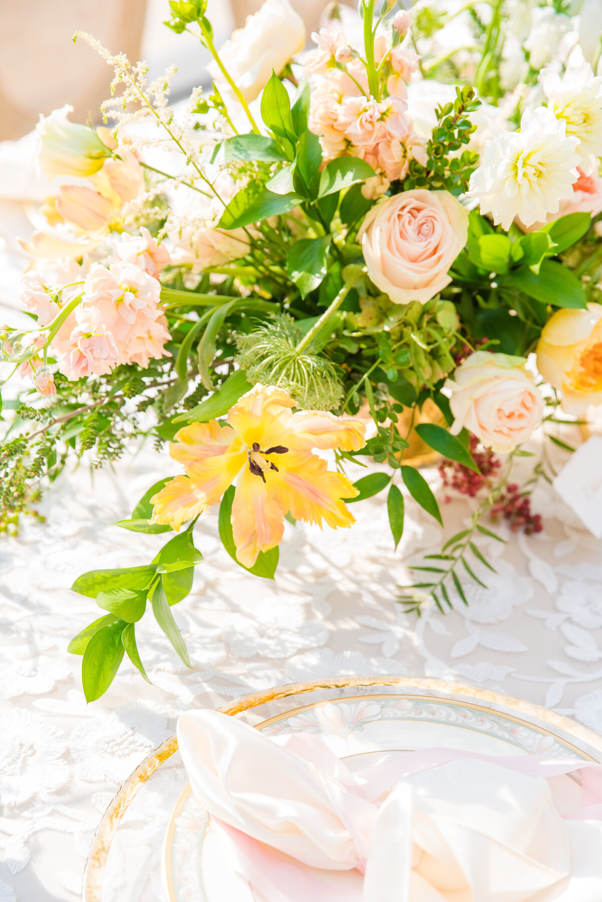 pastel yellow and blush centerpiece with gold rimmed charger and blush napkin