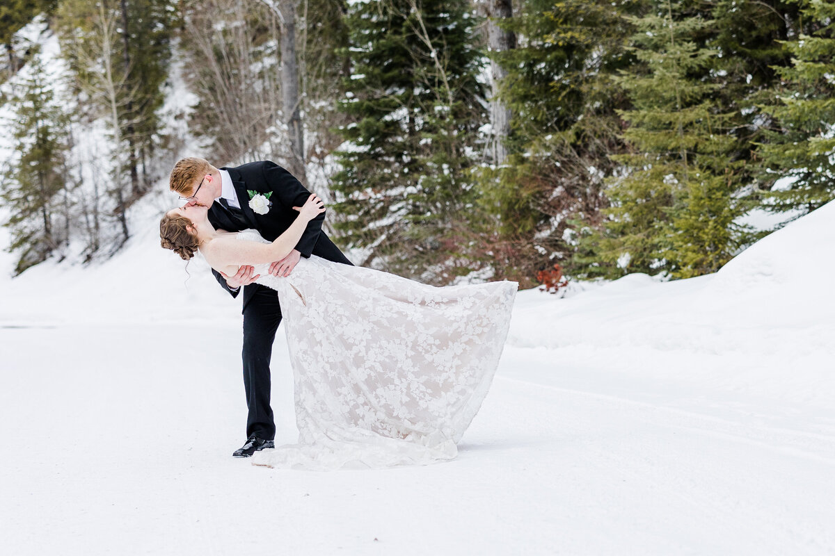 Bride and groom facing each other with arms around each other. Wood fence leading with Mountains in background.