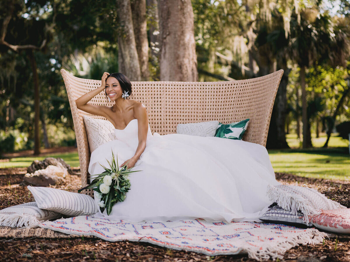 The bride, in her gorgeous gown, is sitting on a native couch in Montage at Palmetto Bluff. Destination wedding image by Jenny Fu Studio