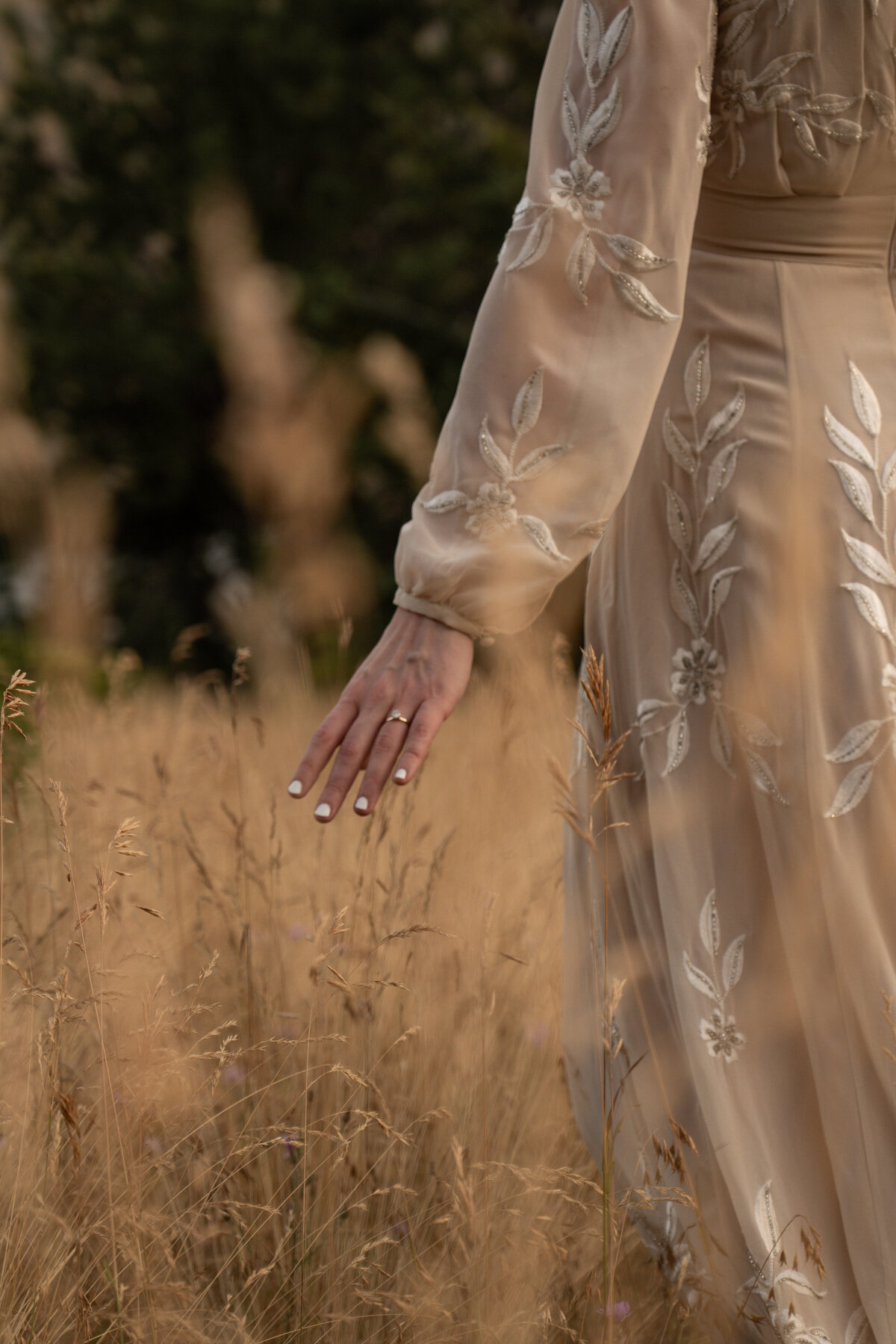 woman in a dress walking through golden field in idaho