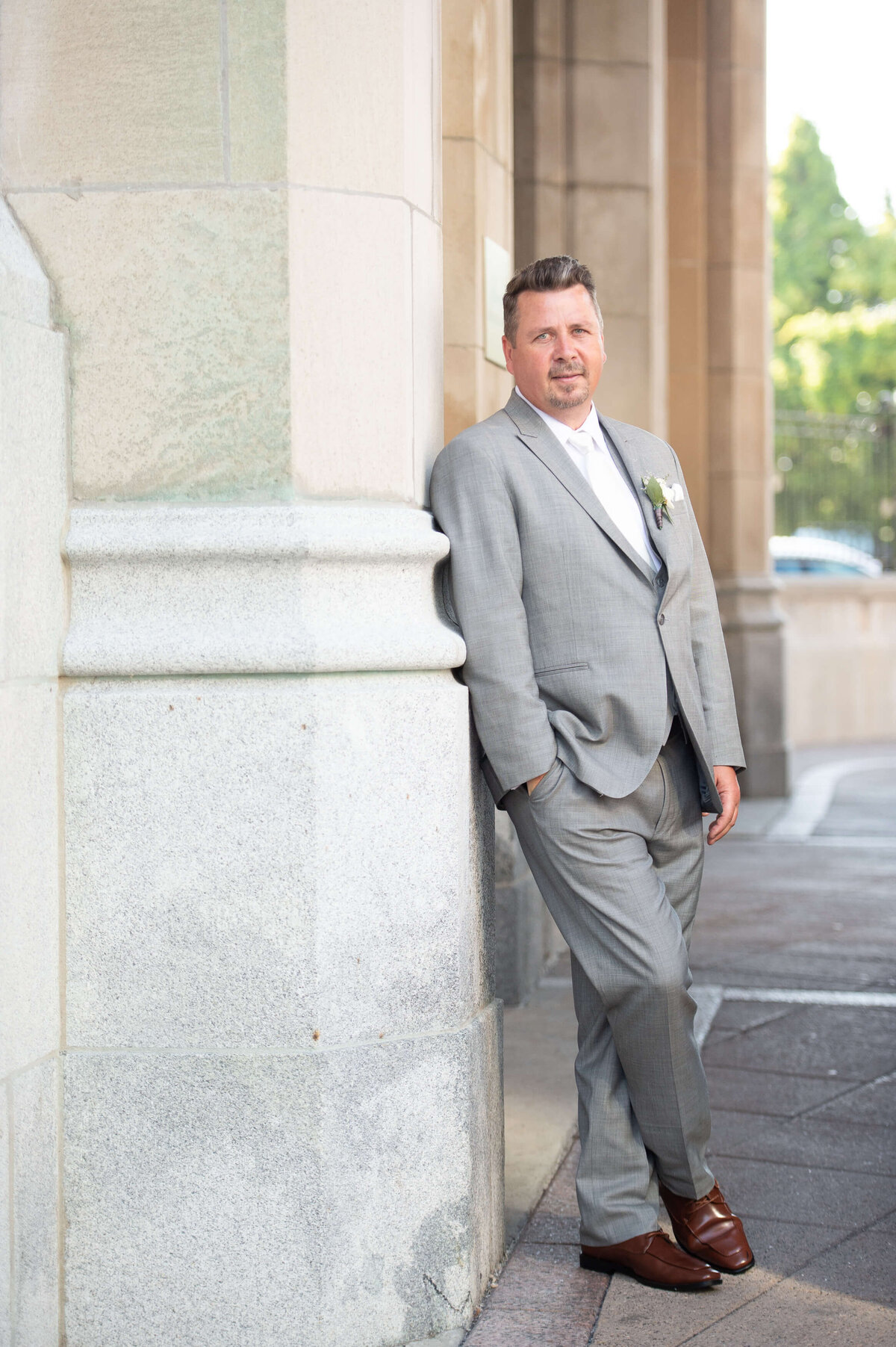 Ottawa wedding photography of a handsome groom  leaning on the pillars outside the Chateau Laurier  wedding venue
