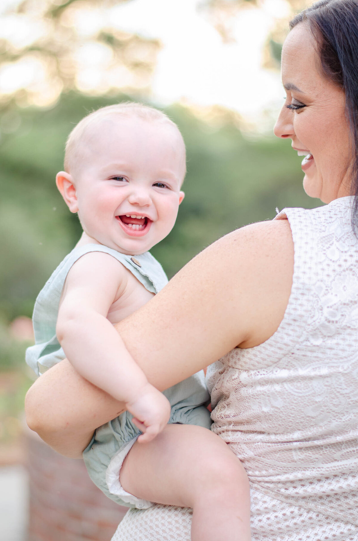 boy smiles on mom's hip in a rose garden