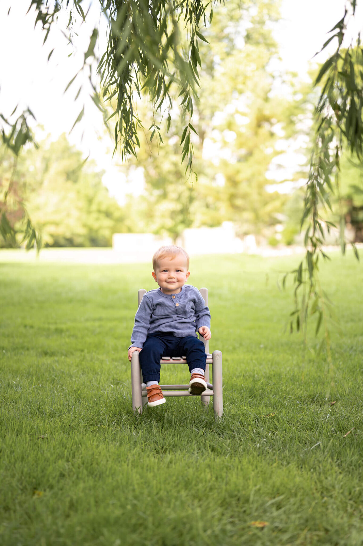 one year old sitting in a chair on the grass