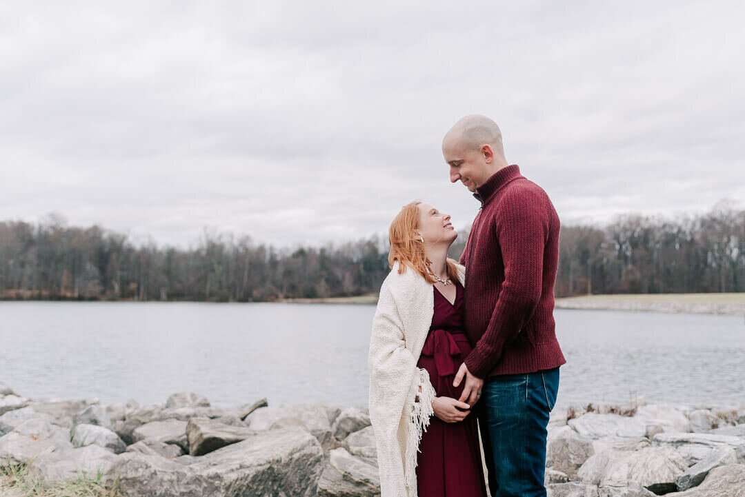 A petite pregnant woman gazing up at her loving husband, taken by northern virginia maternity photographer