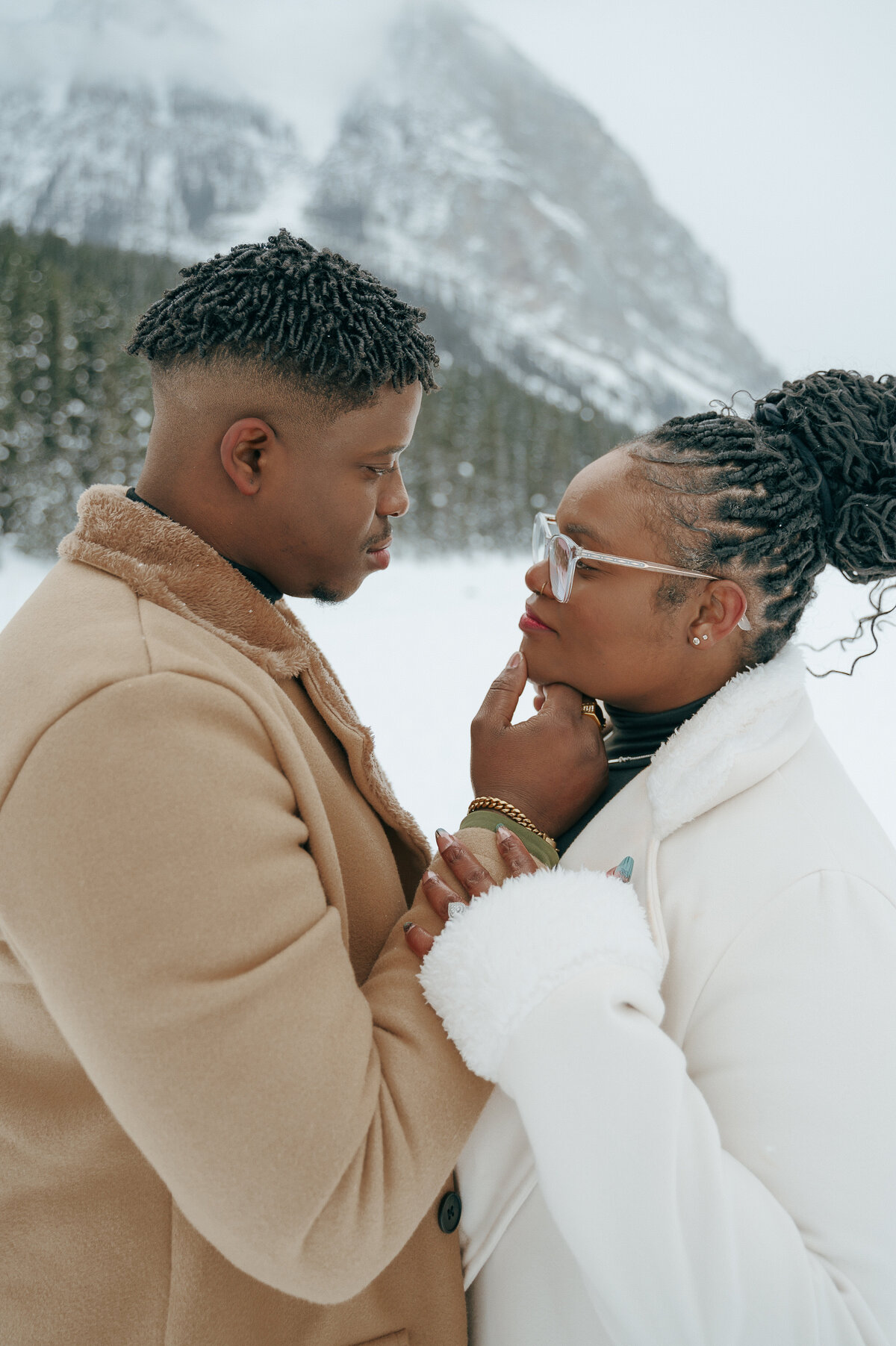 Romantic moment of Black couple embracing during Lake Louise winter session.