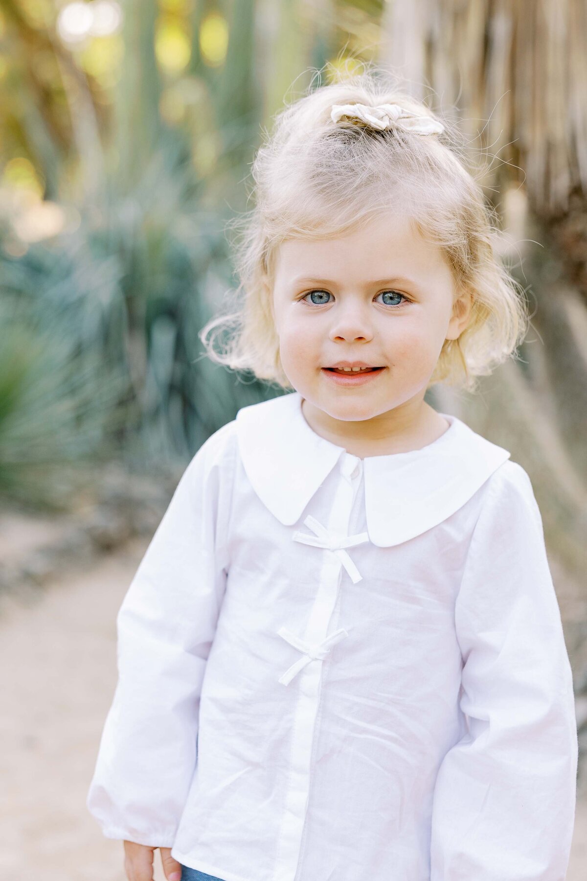 little girl in white shirt looking at camera and smiling