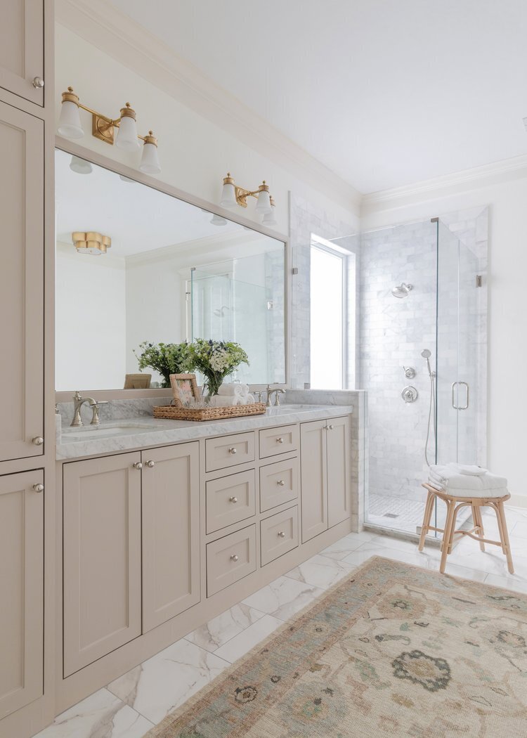 oyster creek studios oak forest remodel tan vanity with marble countertops and rug in bathroom