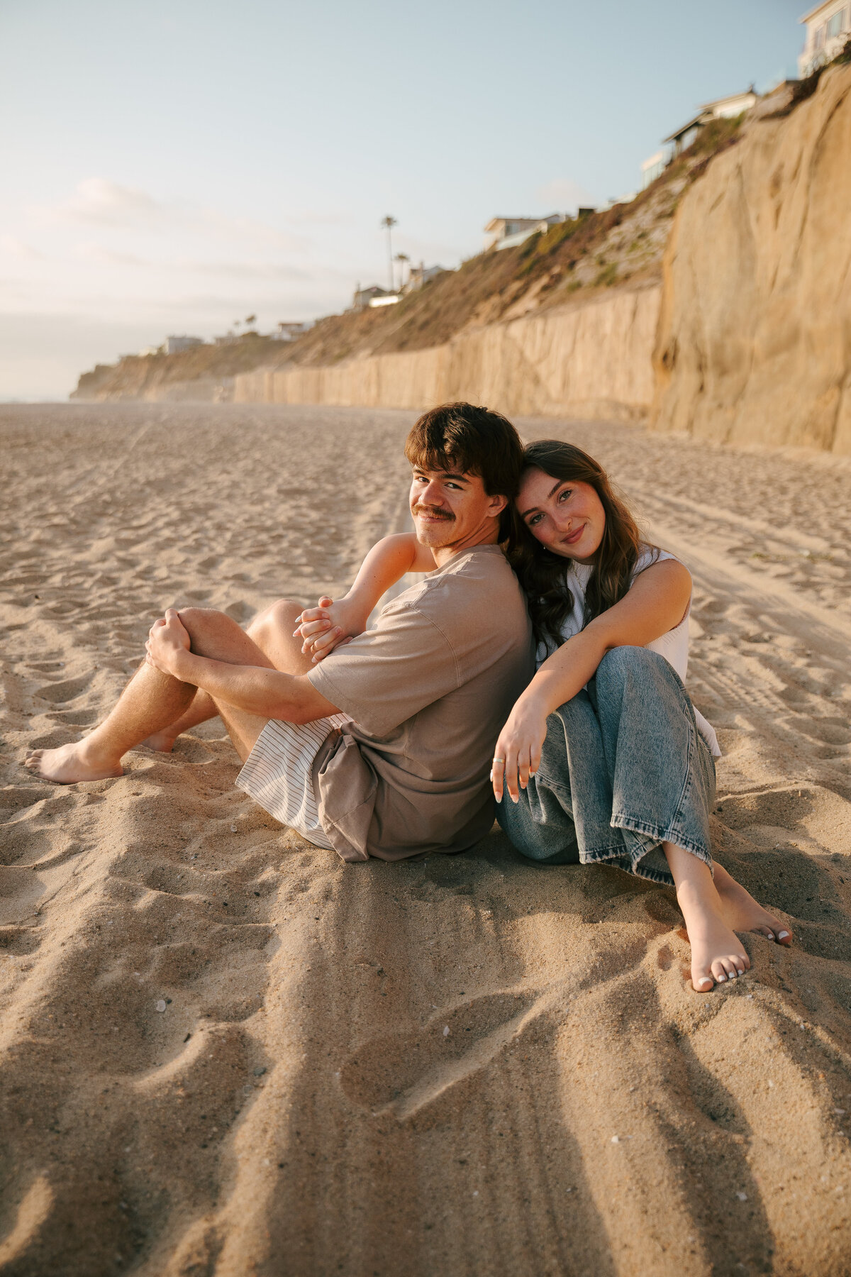 Engaged couple barefoot along Coronado Beach during golden hour in San Diego.