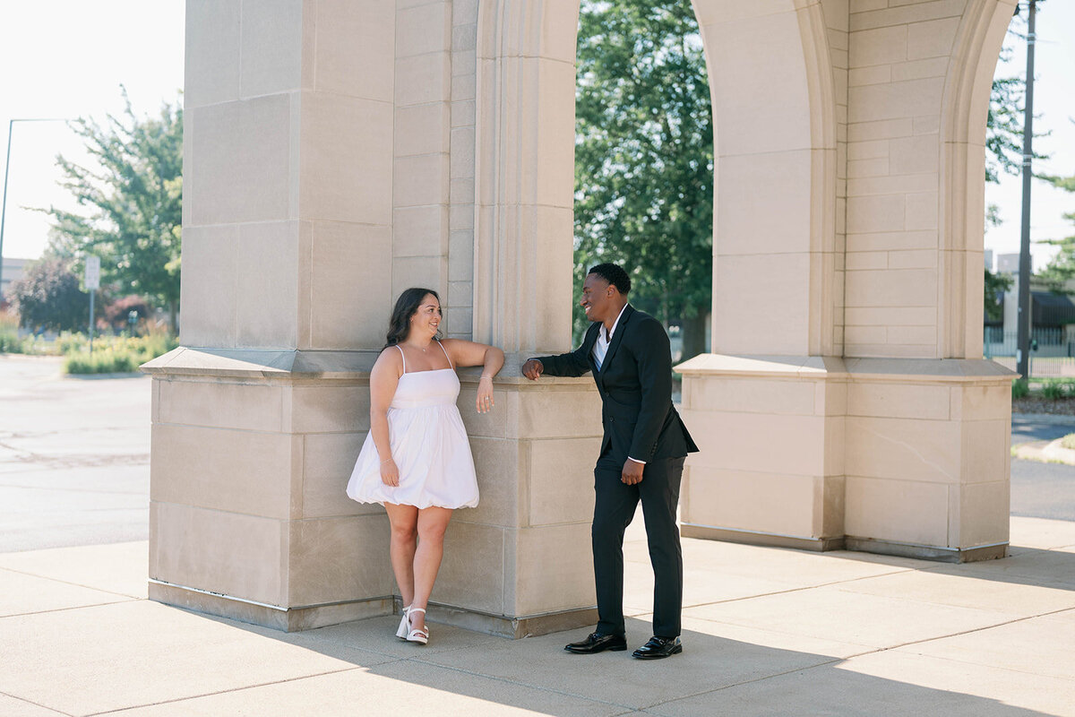 Modern engagement pictures of couple posing by stone columns in downtown Kalamazoo.