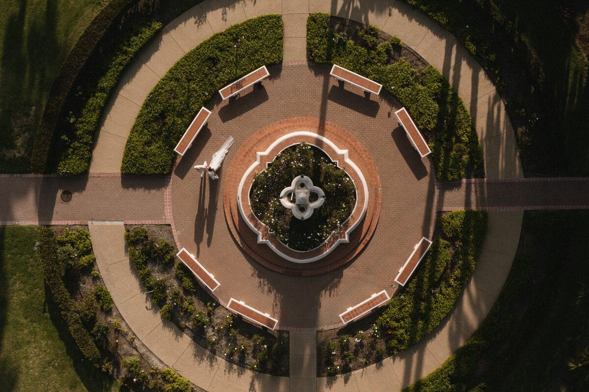 Drone view of bride and groom walking around fountain at Hilton Beachfront Resort Santa Barbara