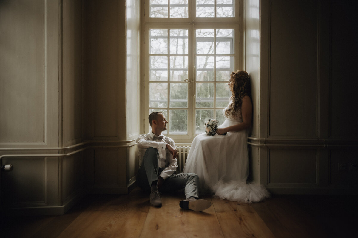 brautpaar-sitzt-vor-grossem-alten-fenster-standesamt-lenzburg-hochzeitsfotograf.jpg