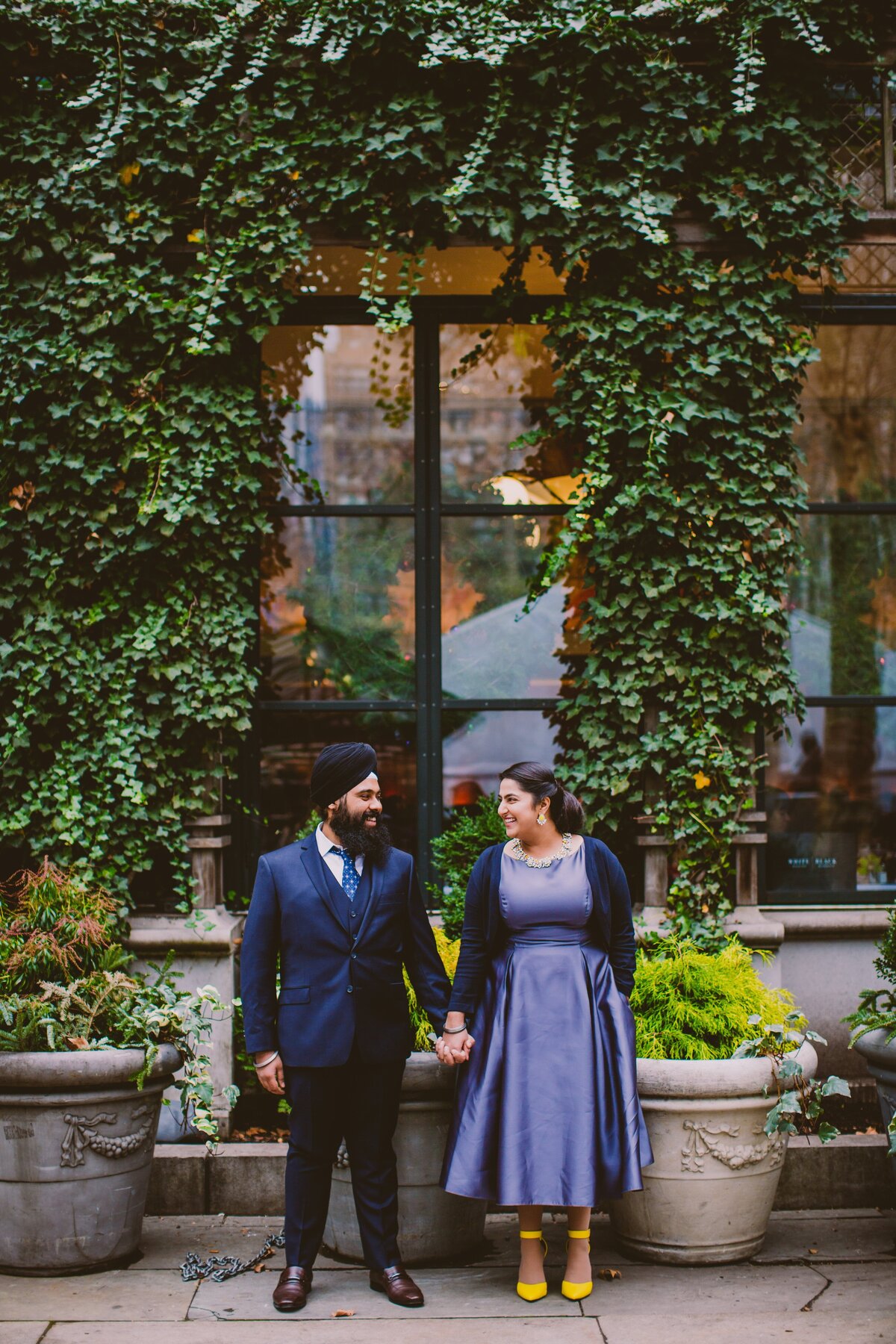 A sikh couple standing outside the bryant park grill in formal clothes during their engagement session in nyc