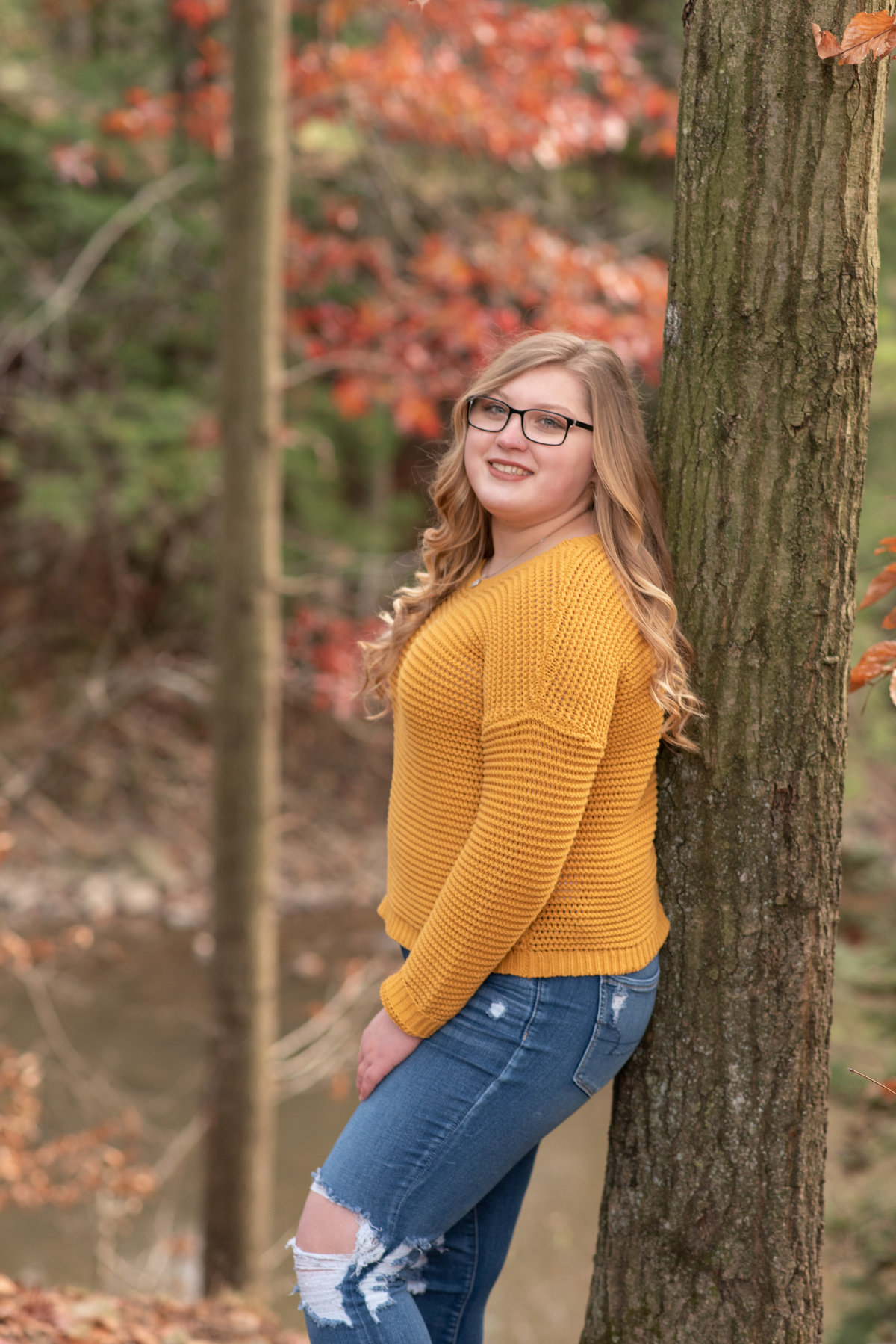 Senior Girl in gold sweater leaning against tree