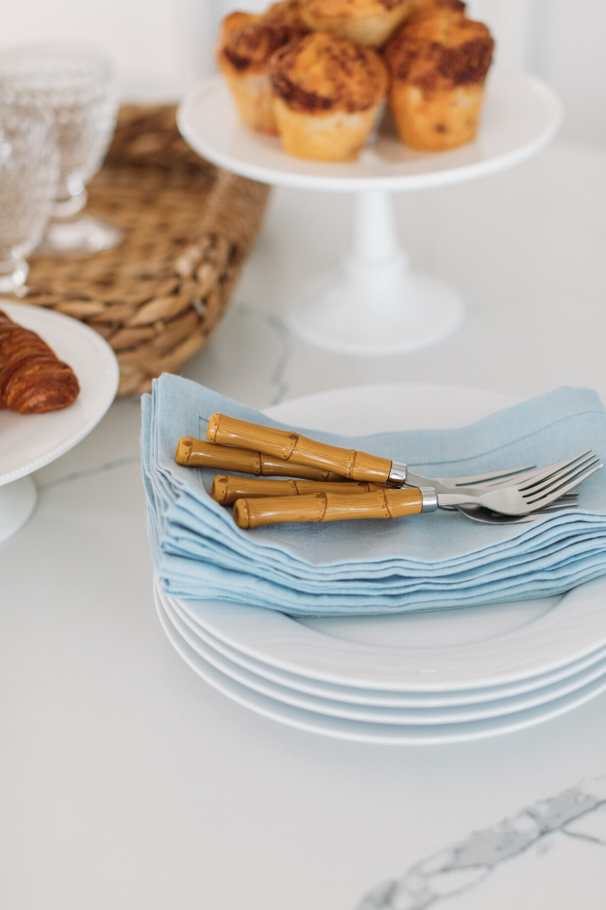 White plates with blue linen napkins and bamboo flatware