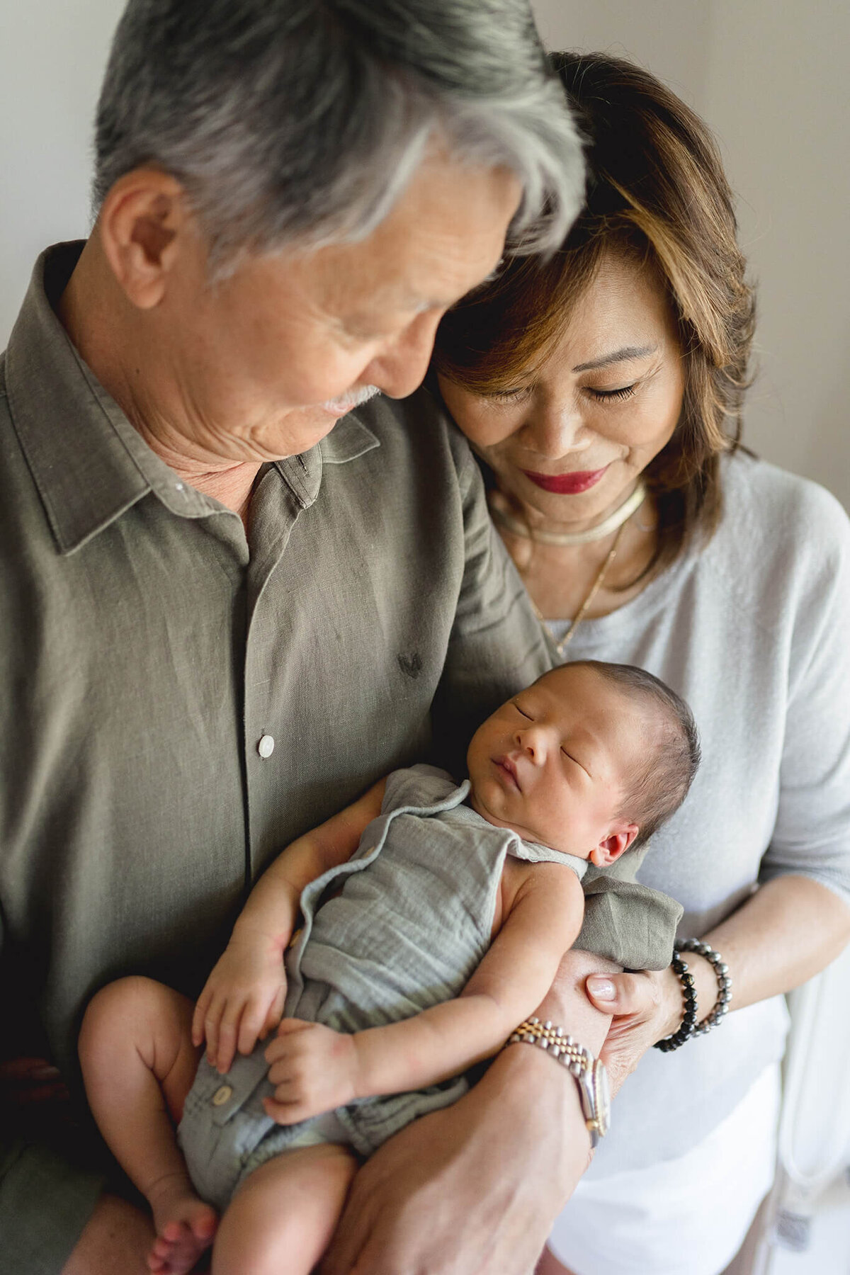 grandparents hold baby boy first time, captured by lifestyle photographer in Gold Coast Hikari Lifestyle Photography.