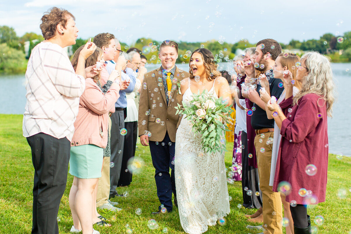 Bride and groom walking down the aisle as guests blow bubbles at them