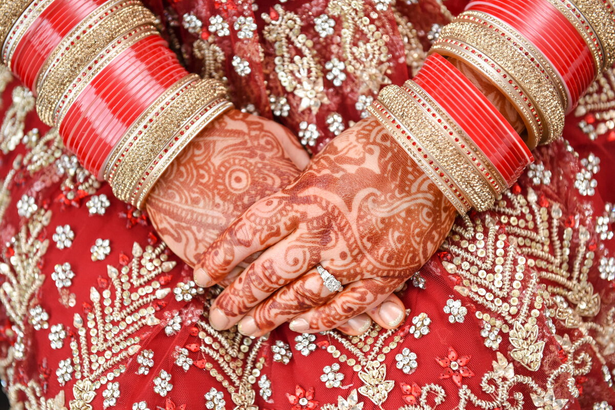 Bride's henna hand and bangles, wedding attire details.