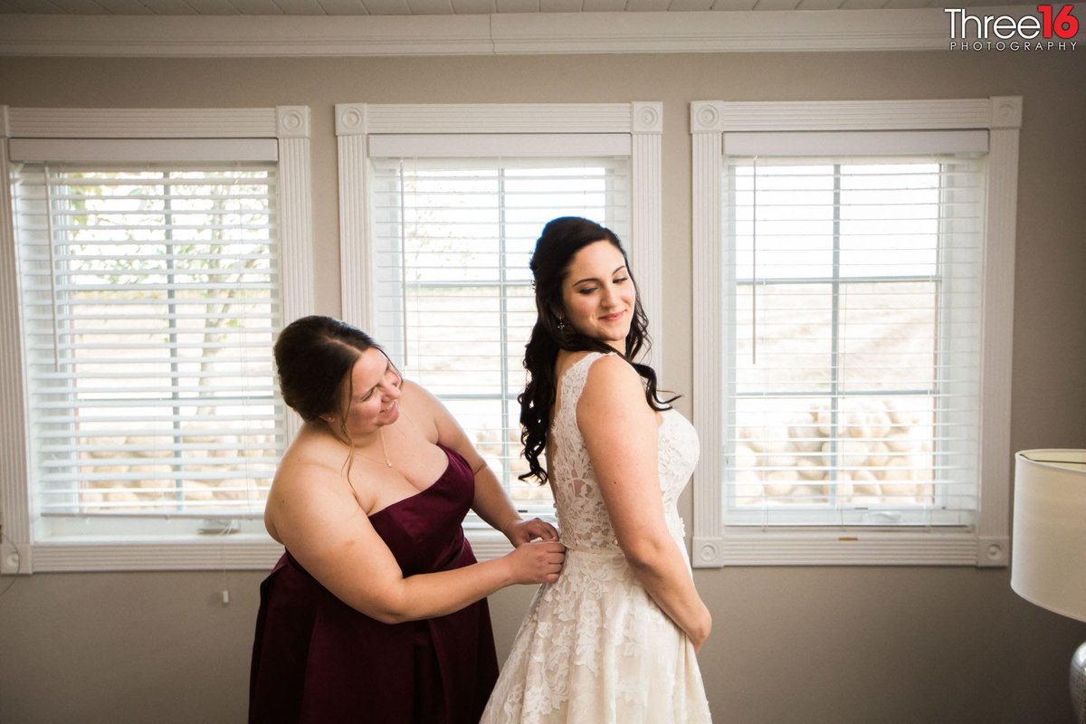 Bride getting buttoned up prior to her wedding