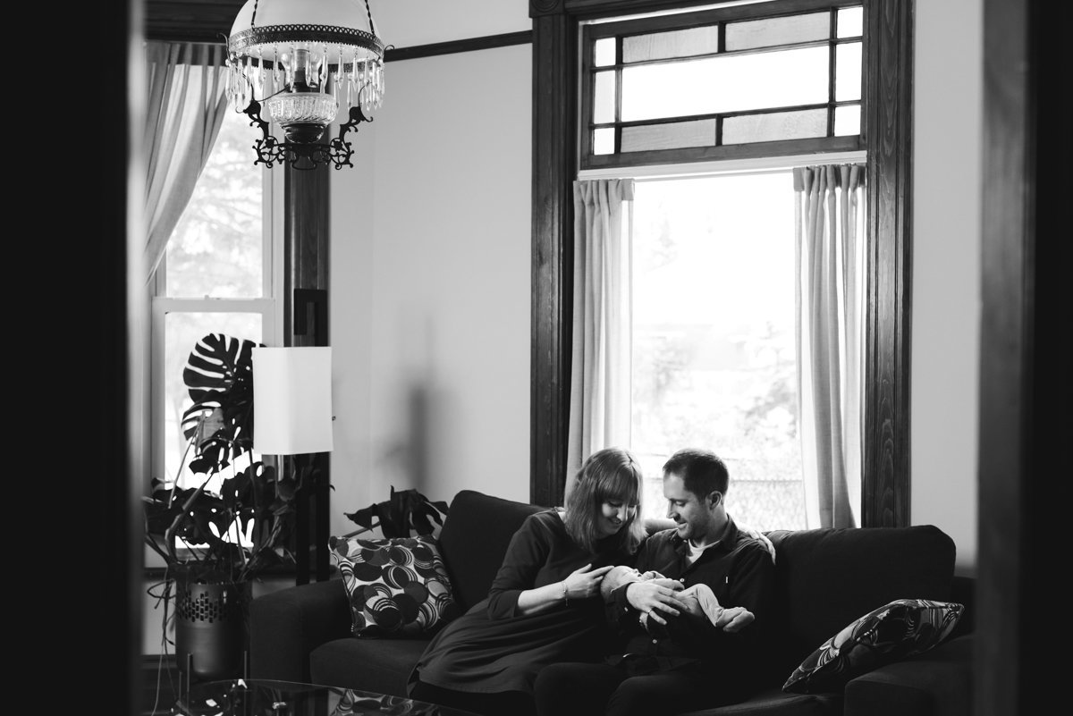 parents with newborn baby sitting on the couch in their living room